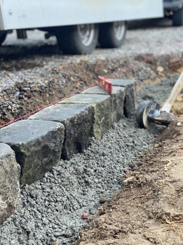 Stone edging blocks set in fresh concrete trench